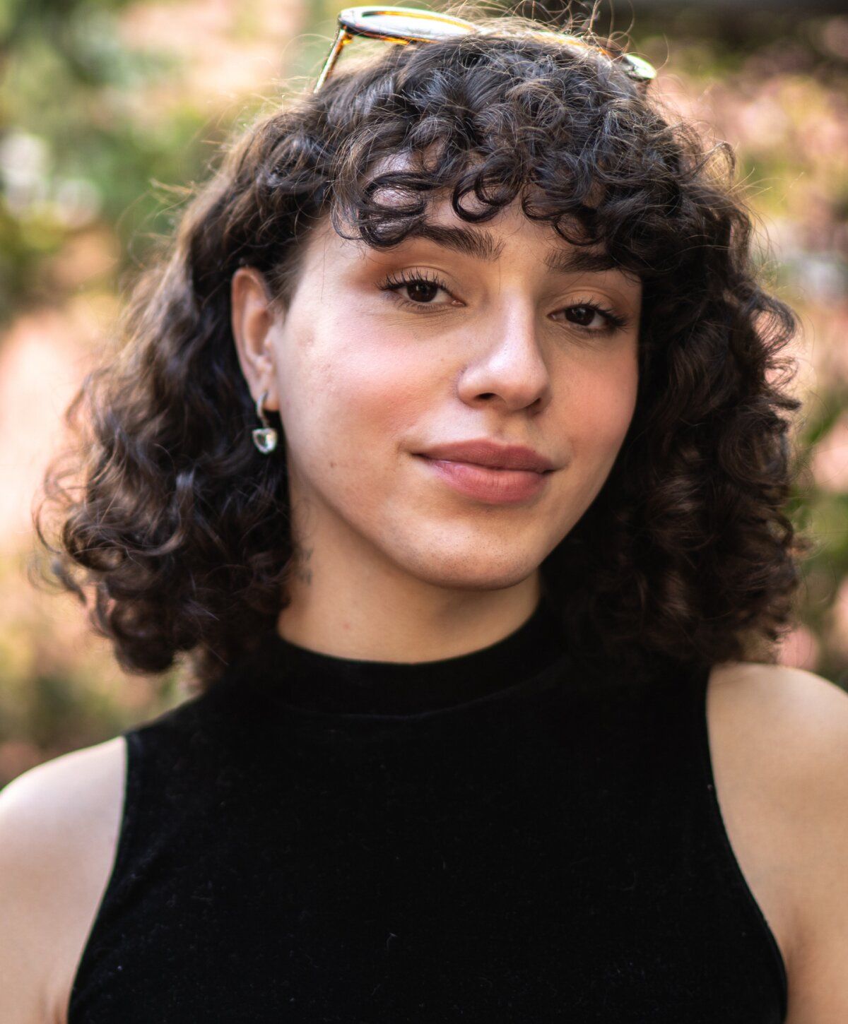 Person with curly hair smiling outdoors.