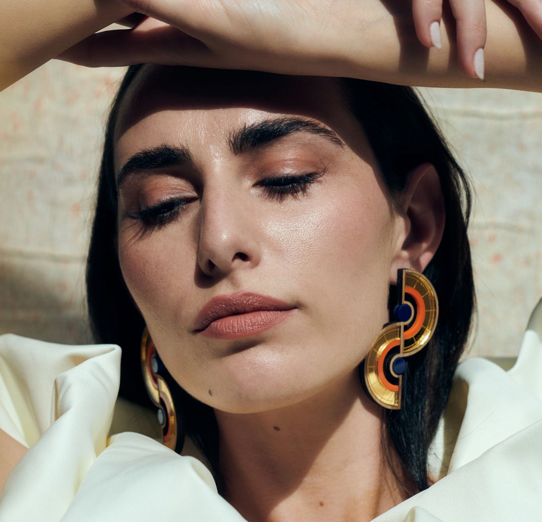 Woman with bold earrings and soft makeup.
