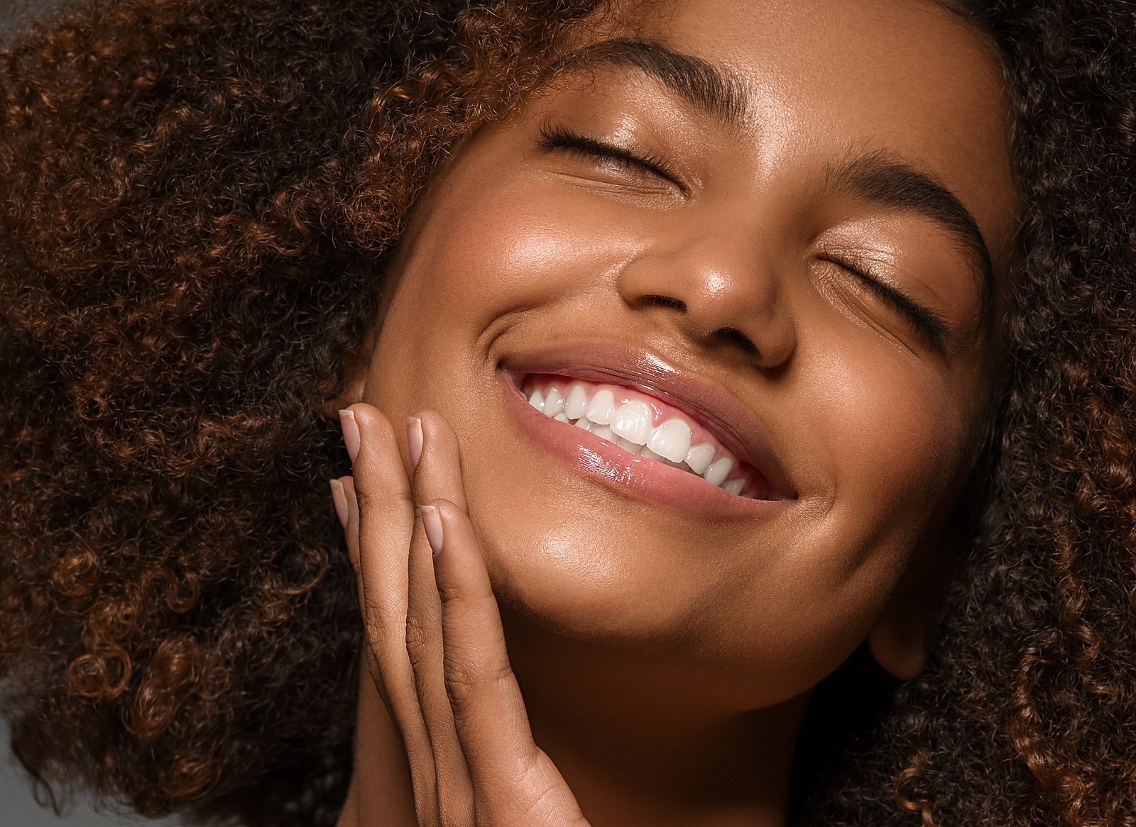 Smiling woman with curly hair, joyful expression.