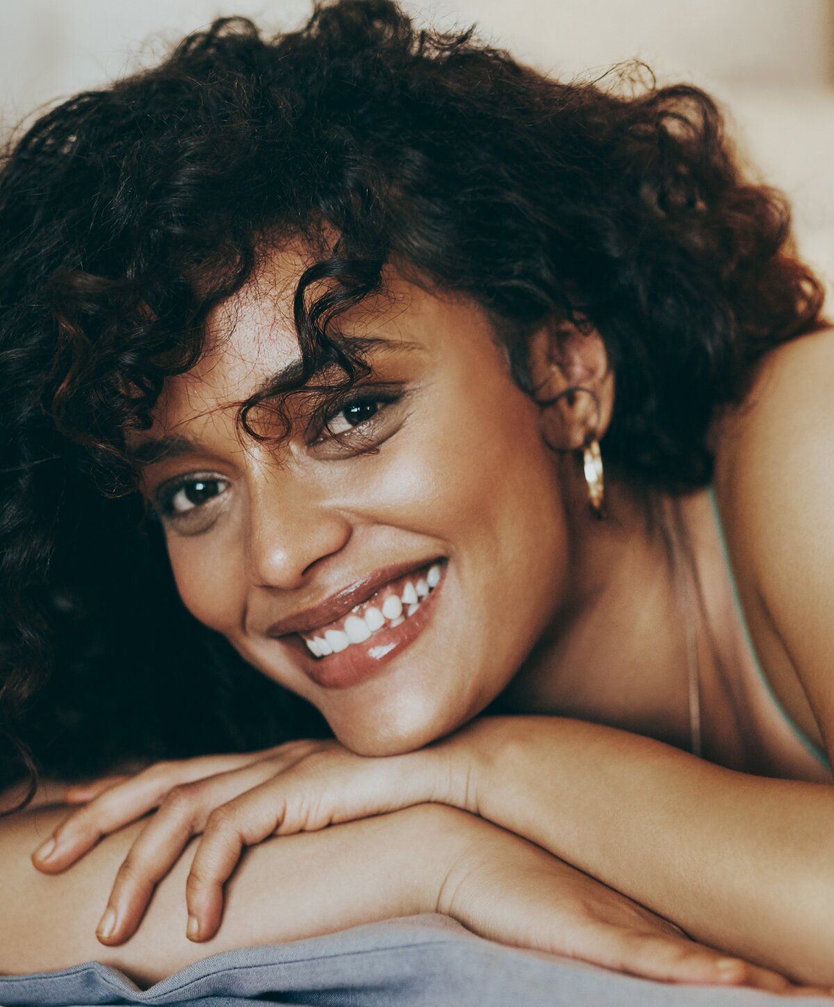 Smiling woman with curly hair resting on hands.