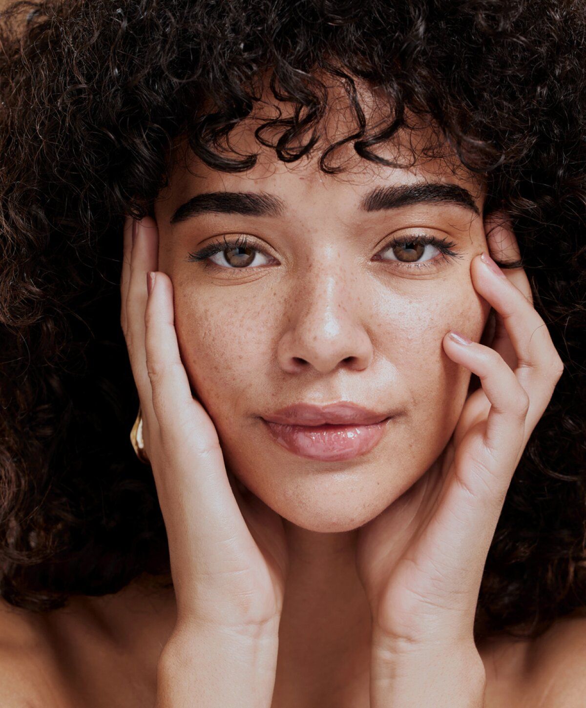 Woman with curly hair and natural makeup.