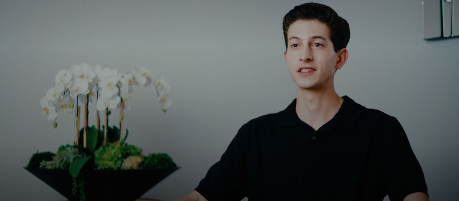 Person sitting near a floral arrangement indoors.